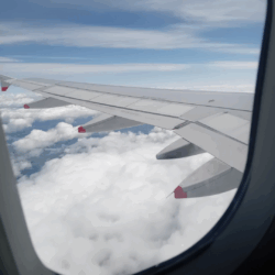 A plane window with a view of clouds