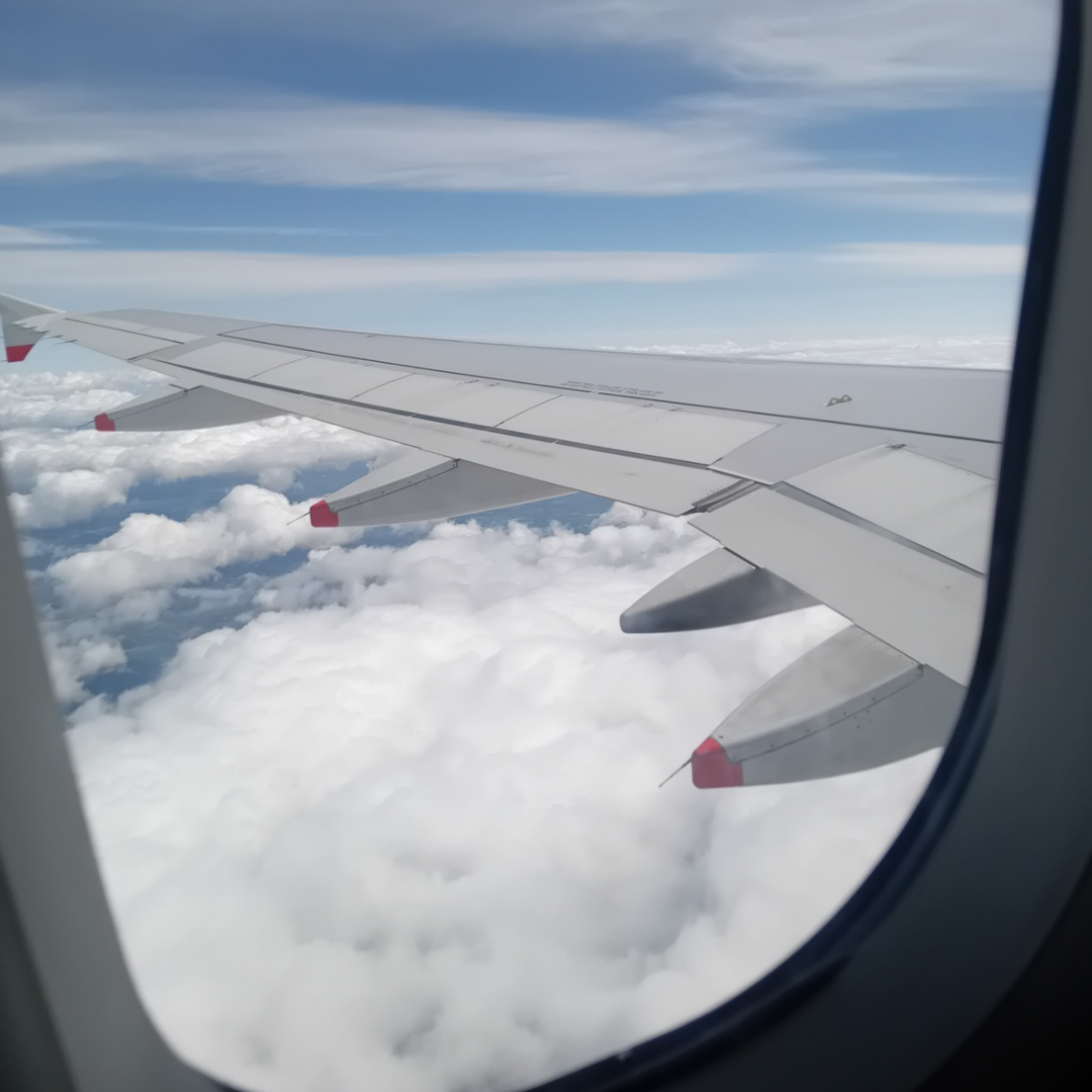 A plane window with a view of clouds