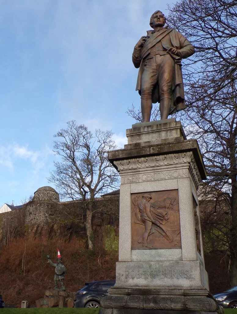 Robert-Burns-statue-with-statue-in-the-distance-with-a-traffic-cone-on-its-head-after-Hogmanay